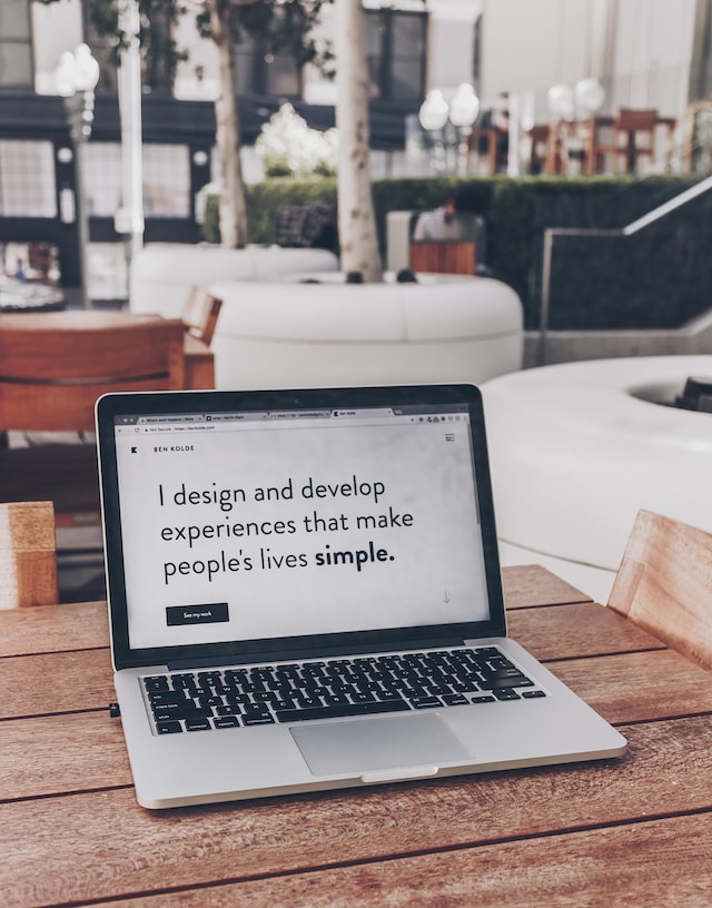 A switched-on Macbook, with text on the screen reading, "I design and develop experiences that make people's lives simple."