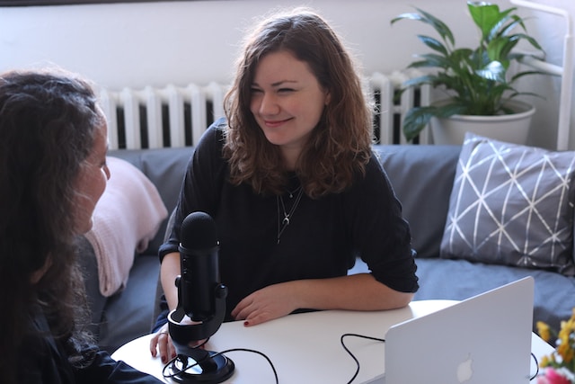A woman in a black shirt smiles while interviewing a prospective user. 
