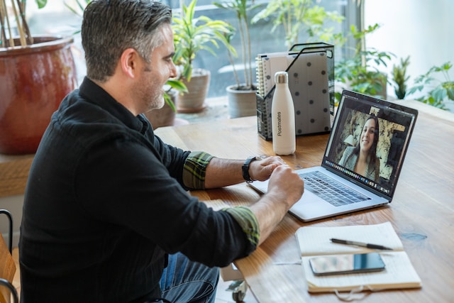 Man in a black sweater on a video call on his laptop.