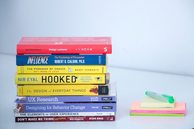  A stack of books about product design and UX on a white table.