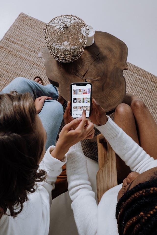 Two women use a smartphone, pointing at an app on the screen.
