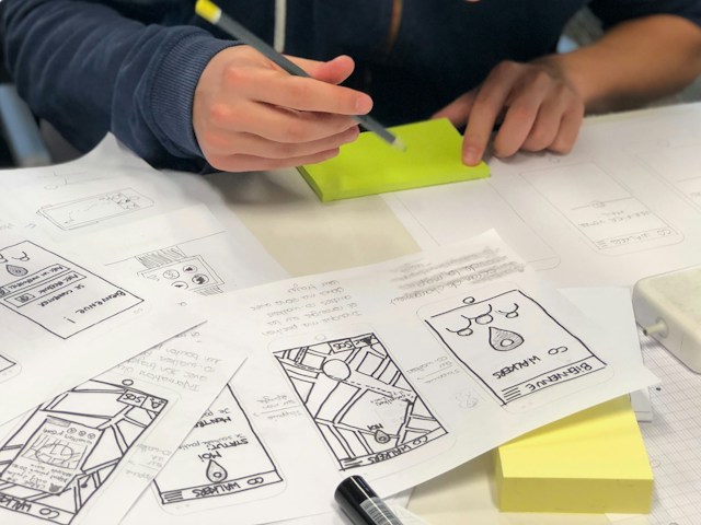 A person sketching wireframes on paper.