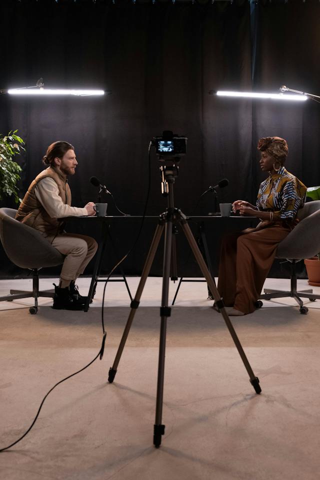 A black video camera points to a man and a woman engaged in a user interview.