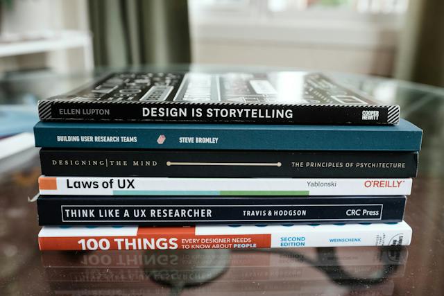 A stack of UX design books sits on a table. 