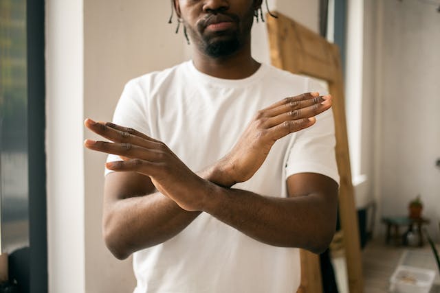 Man showing stop gesture with crossed hands.