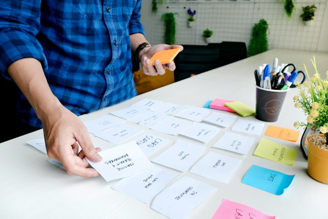 A person organizes white pieces of a card into categories as part of a card sorting exercise.
