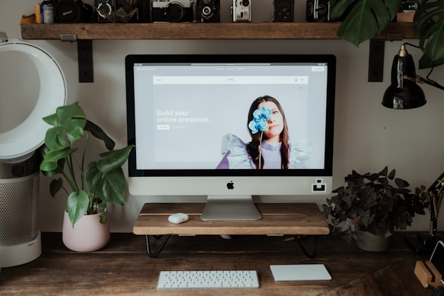 A turned-on iMac on a wooden desk with the Squarespace homepage open on the screen.
