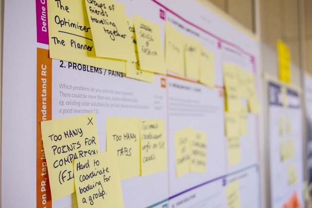 A close-up of a board with several sticky notes on it. The sticky notes contain feedback concerning a digital experience. 
