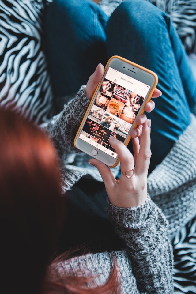 A person holds a turned-on smartphone and touches the screen as if scrolling.