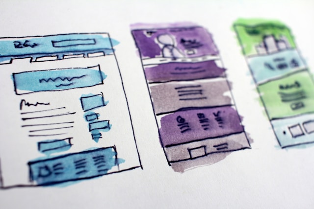 Three colorful wireframes sketched onto white paper.
