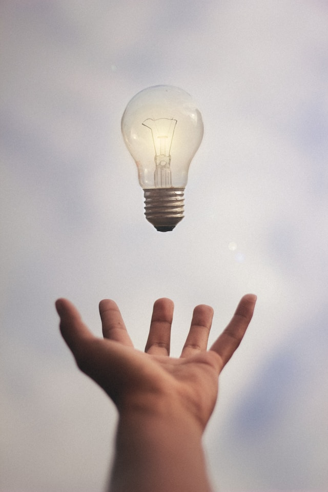 A person’s arm extends to catch a bright lightbulb.
