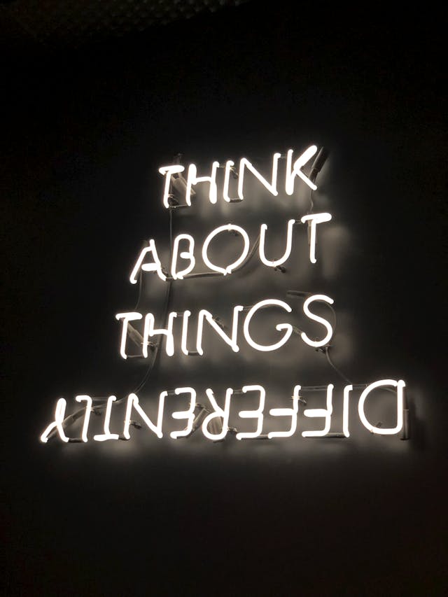 Turned-on neon signage that reads, "Think About Things Differently." "Differently" is upside-down.

