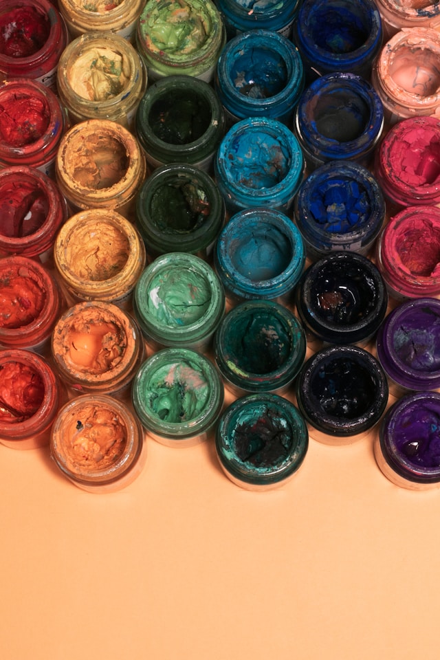 A close-up of a multitude of plastic containers containing differently colored paint. 
