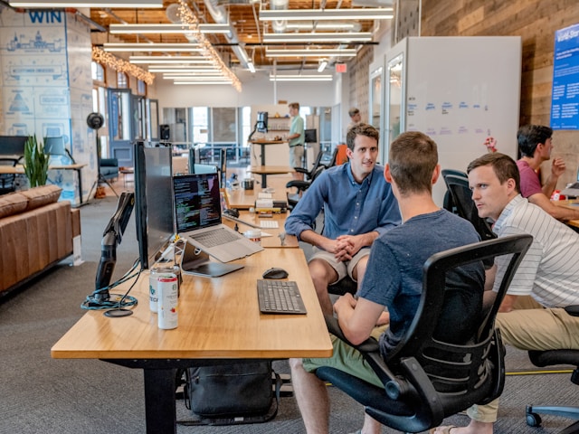 A team of people sit around a table with their laptops, brainstorming ideas