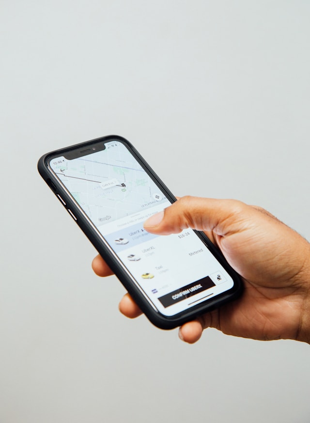 A person holds a smartphone with the Uber app open on the screen.
