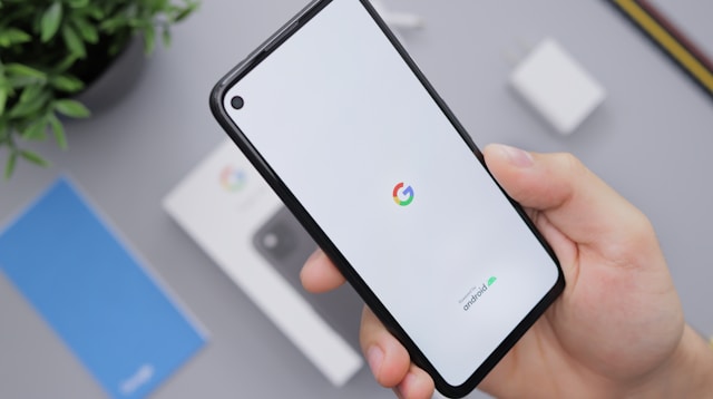 A person holds a turned-on Android phone open on the Google loading screen.
