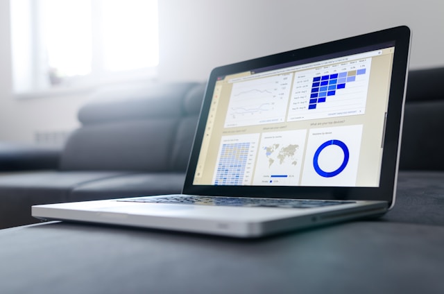 A turned-on laptop with an analytics dashboard on the screen representing different data.