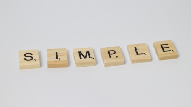 A close-up of several Scrabble tiles with the word ‘Simple’ on a white background.