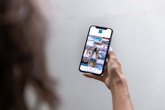A person holds a smartphone against a white background, with Instagram on the screen.