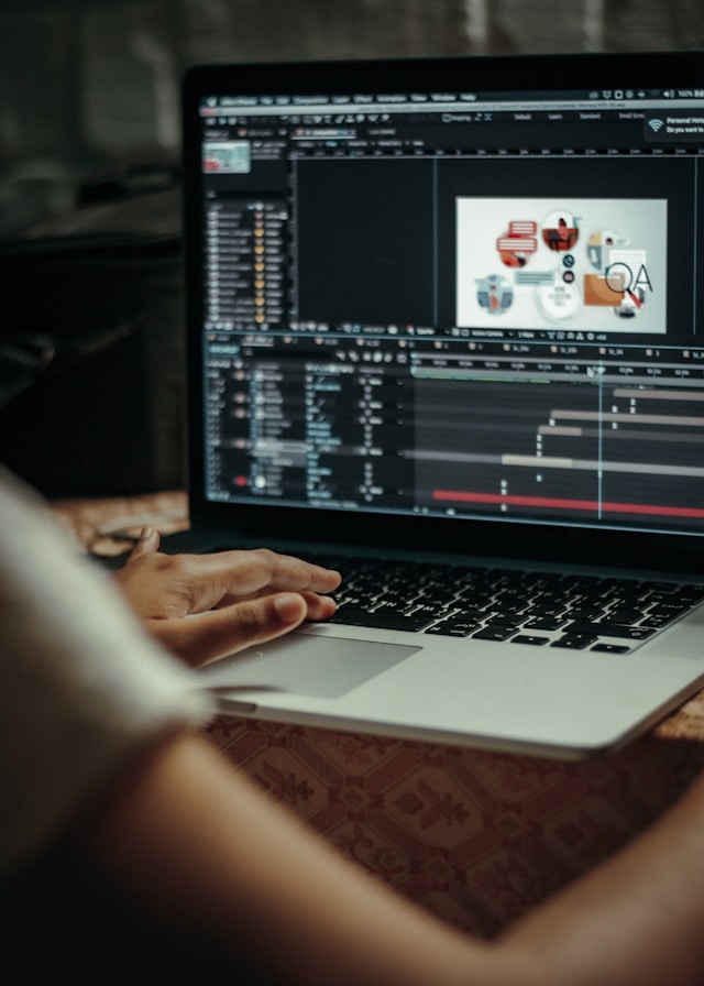 A person sits at a table, using a silver Macbook Pro to create animations. 