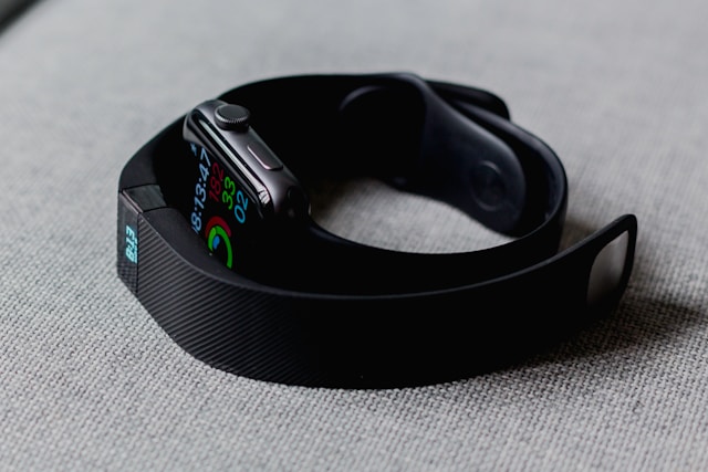 A Fitbit and an Apple watch on a gray background.
