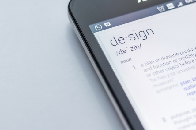 A close-up photo of a phone showing the corner of the screen. The definition of the word "design" is on the screen.
