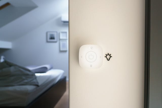 A smart thermostat on the wall of a bedroom.
