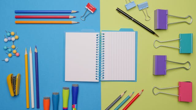 A display of colorful office supplies, including a notebook and colored pencils. 
