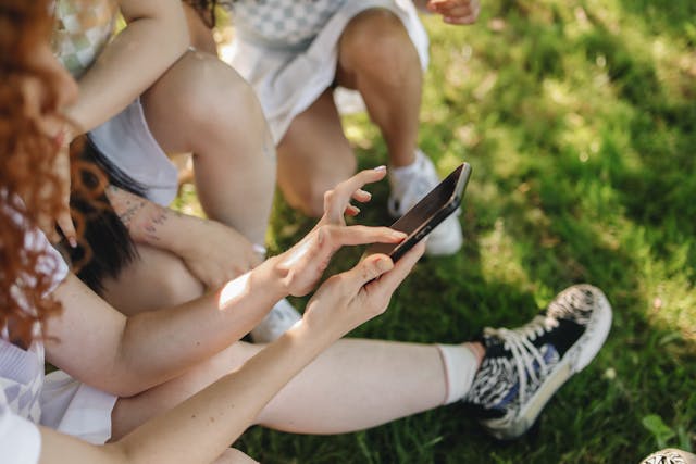 A side view of a person tapping their phone screen, surrounded by other people. 
