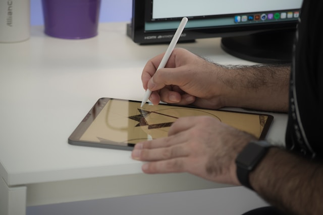 A man drawing on a turned-on tablet with a stylus.
