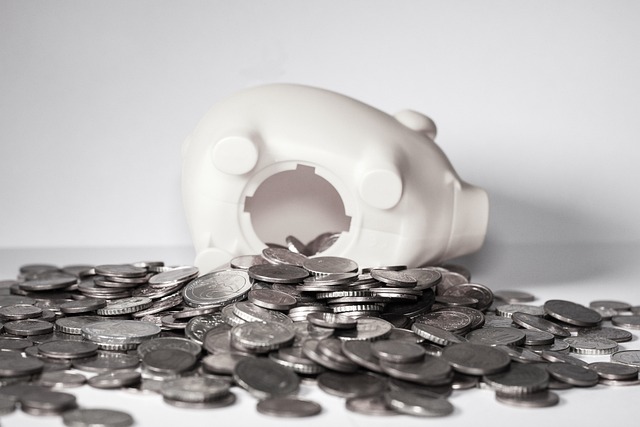 A white piggy bank lies on its side, surrounded by an abundance of silver coins. 