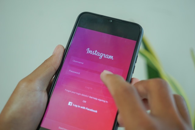 A person holds a smartphone with Instagram’s colorful login screen on it.