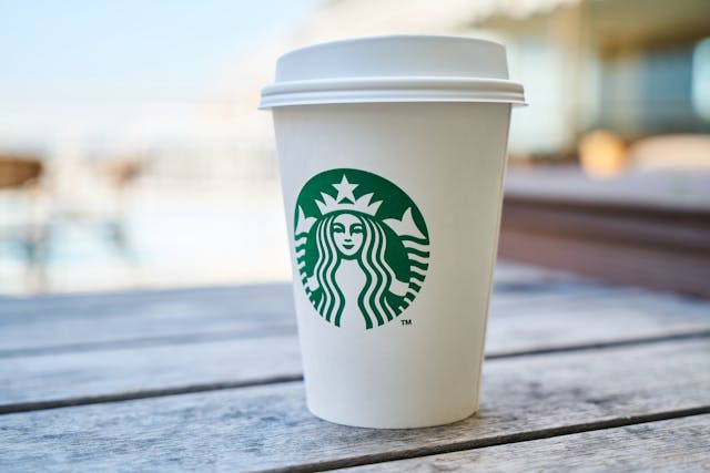 A close-up of a coffee cup with Starbuck’s easily recognizable logo on it. 