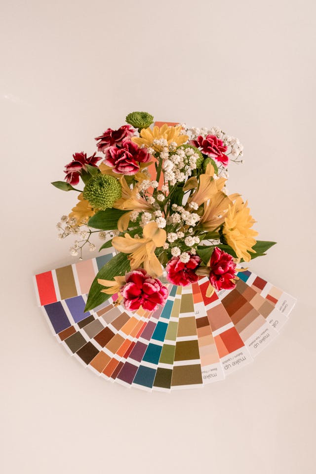 A birds-eye view of vibrant, differently colored flowers and a fanned-out color palette below it. 