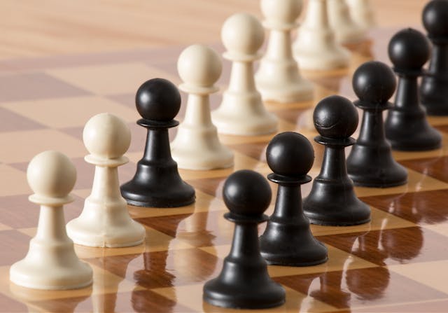 A black pawn stands aligned with a row of white pawns on a chessboard to symbolize contrast. 
