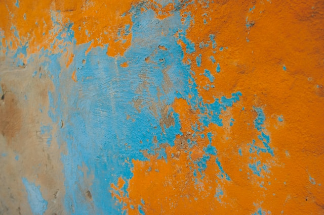 An image of an orange and blue wall with peeling paint to represent varying color temperatures. 