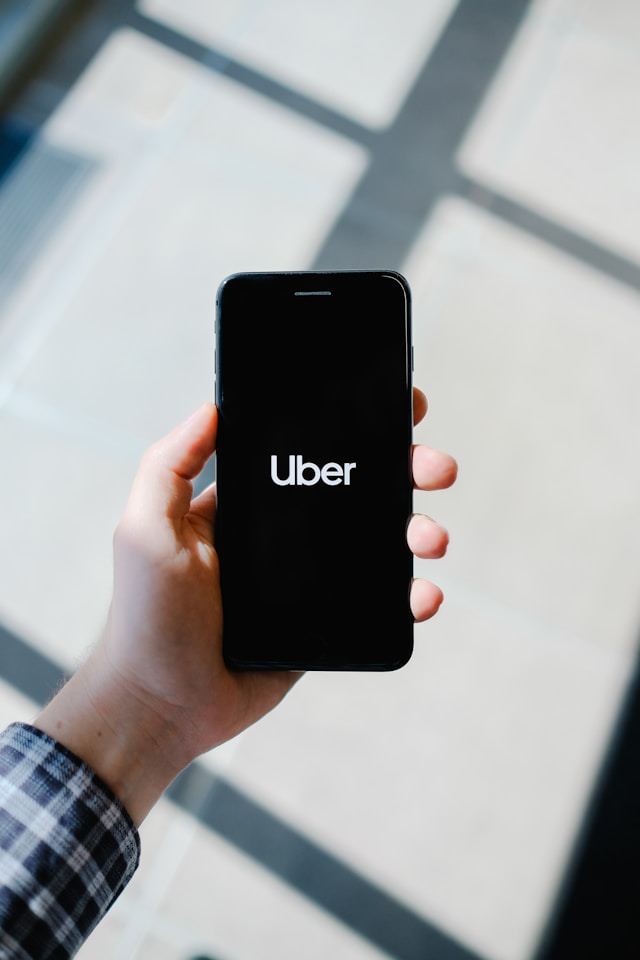A person holds a turned-on phone showing the Uber loading screen.