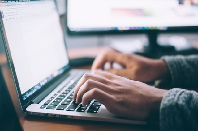 A close-up of a person typing on a laptop keyboard.
