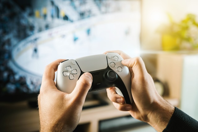 A person holds a white PlayStation controller in both hands.
