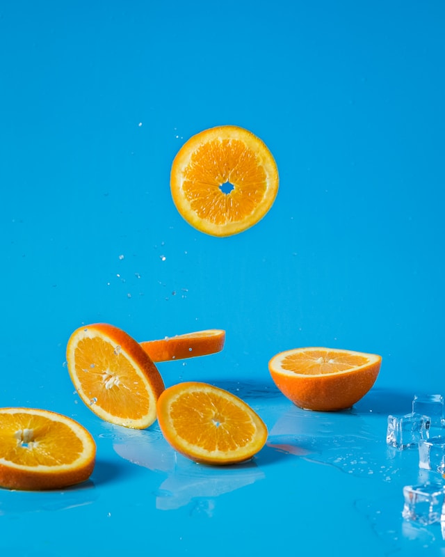 A couple of vibrant orange slices against a bright blue background. 
