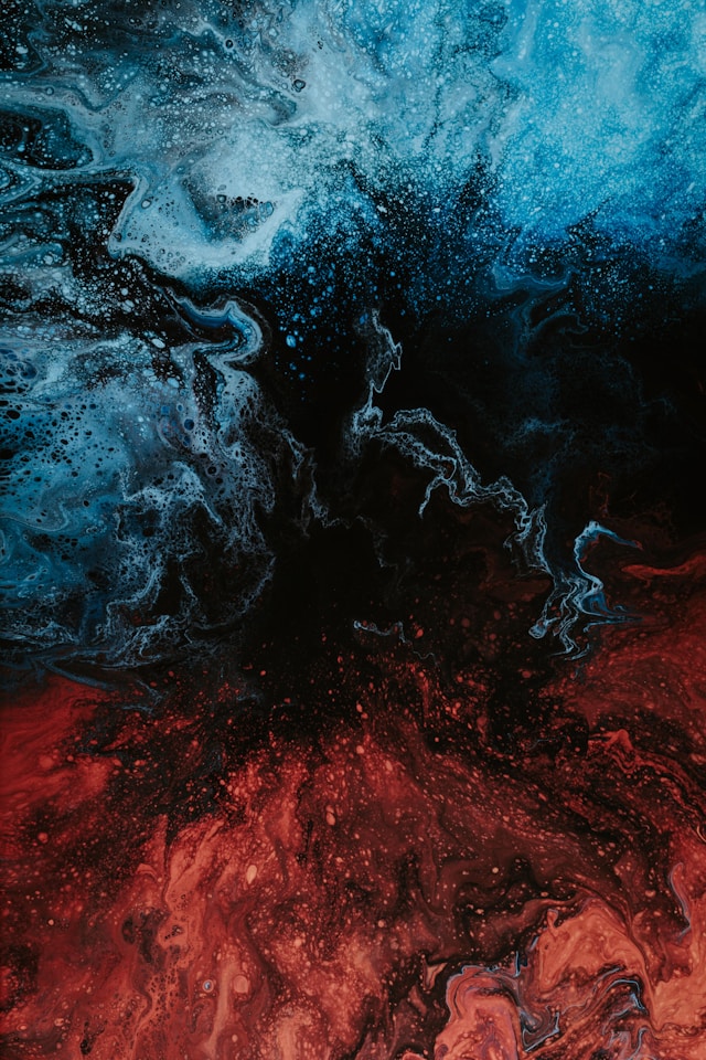 A colorful background where a blue liquid mixes with a red liquid. 
