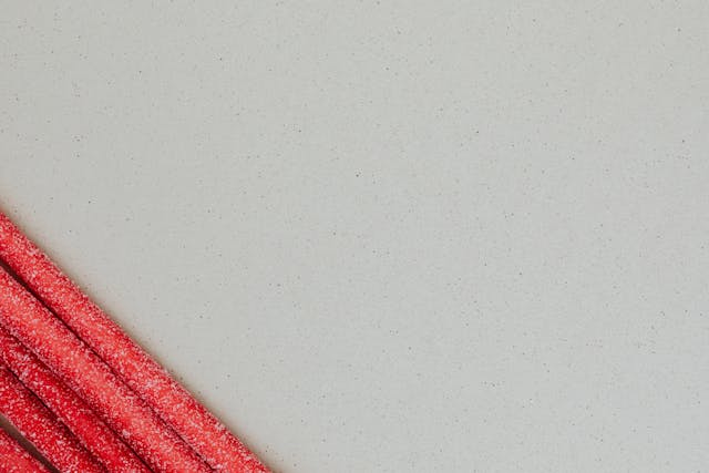An image of long red strips of candy against a grey background. 