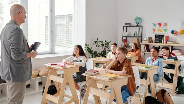A teacher stands in front of a classroom full of young students.
