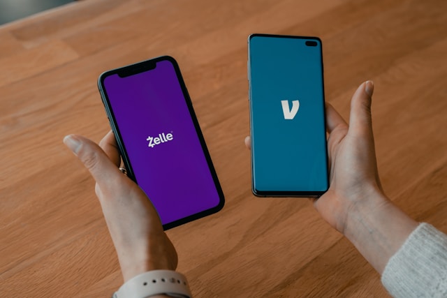 Stock image of a person's holding a smartphone in each hand showing Zelle and Venmo login logos.