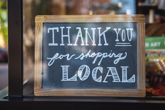 A sign in a store window that says “Thank you for shopping local.”