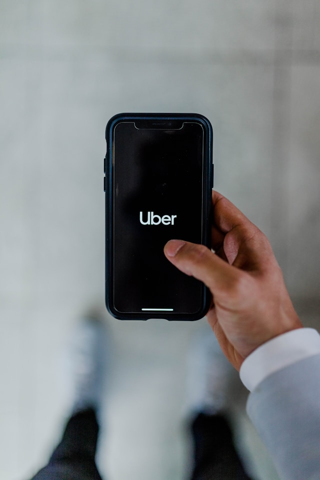 A person holding a phone with the Uber logo on the screen.