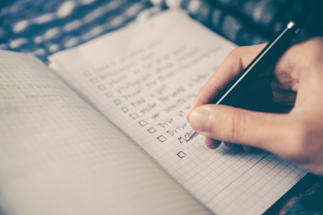 A person writing a checklist in their journal.