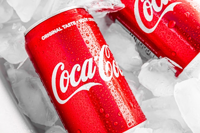 Two red Coca-Cola cans on ice.