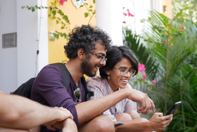 Two people laughing while looking at a phone screen.