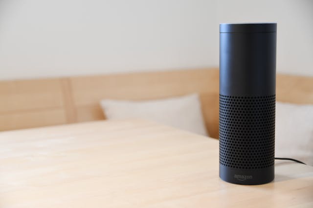 A black Amazon Echo Plus device sitting on a wooden table. 